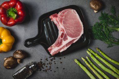 Organik sebze malzemeleriyle çevrili bifteği hazırlamak için çiğ domuz eti manzarası..