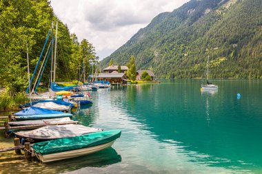 Avusturya 'da Weissensee' nin doğu kıyısındaki tekne iskelesinde yelkenli ve kürek.