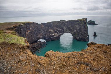 Yazın İzlanda 'nın güneyindeki Reynisfjara kara plajındaki doğal kemerlere bakın.