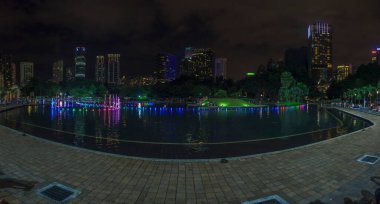 Kasım 2013 'te Malezya' nın Kuala Lumpur kentindeki KLCC Parkı 'nda gece vakti gölde su yansıtan renkli bir çeşmenin fotoğrafı