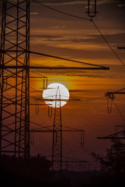 Gün batımının önündeki elektrik direkleri arka planda