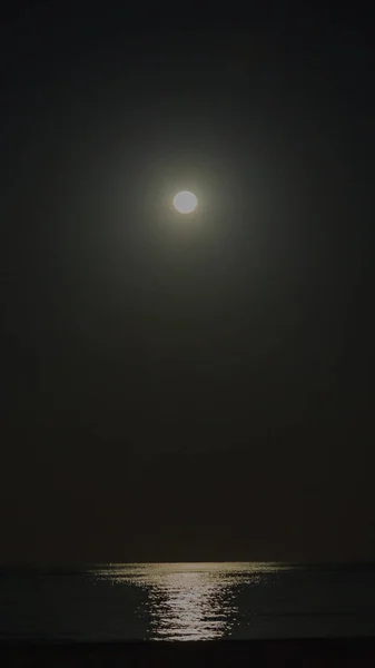 Picture of the full moon over the sea at night with intensive illumination in the water in cloudless skies