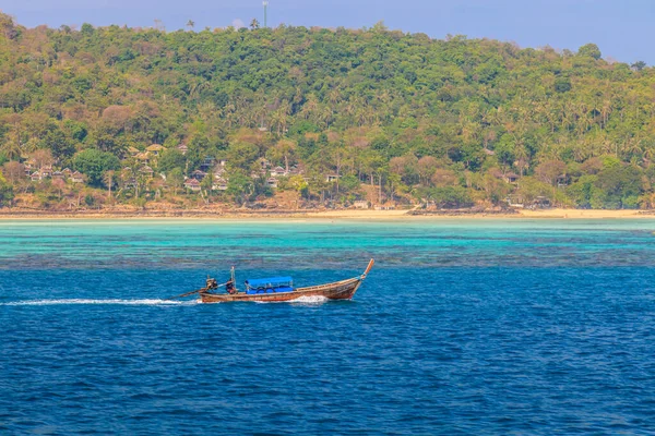 Arka planda tropik ada ve plajla yelken açarken tipik bir uzun kuyruklu teknenin fotoğrafı Kasım 2013 'te Tayland' da öğleden sonra bulutsuz gökyüzünde çekildi.