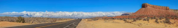 在2013年1月拍摄的照片中 一条穿越内华达沙漠的公路在冬季从很远的地方看到了美国积雪覆盖的山脉 — 图库照片