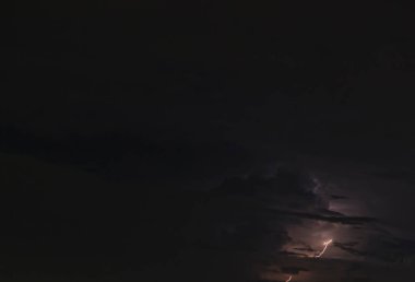 Gece gökyüzünde parlayan bulutların olduğu bir ışık resmi.