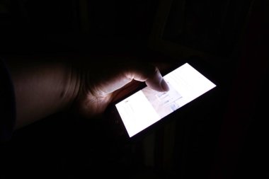 Karanlıkta cep telefonu kullanan adamlara yaklaş.