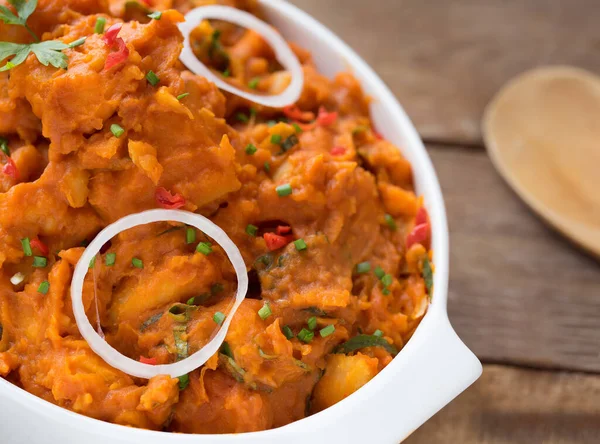 Lezzetli Yam Pottage yemeği veya yeşil baharatlı biber ve ahşap masaya yerleştirilmiş soğan halkaları ile Nijerya lapası.