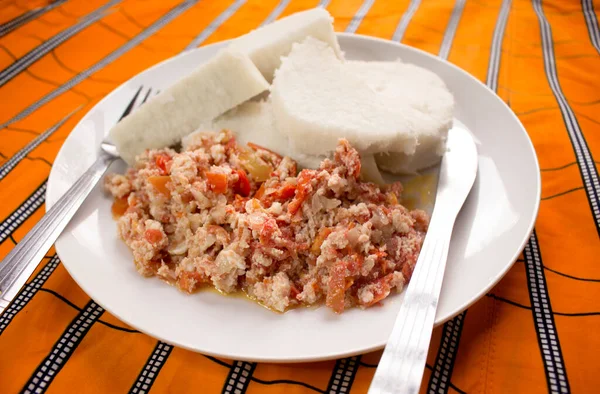 Pişmiş yer elması ve lezzetli omlet, beyaz bir tabakta servis edilir. Renkli turuncu çizgili masa örtüsü, yanına çatal ve bıçak yerleştirilir.