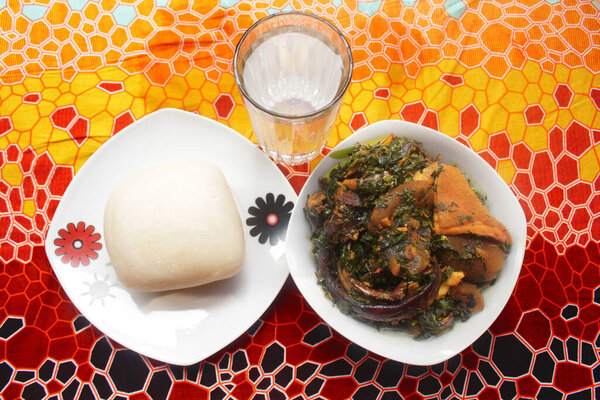 Top view of a served dish of pounded yam and thick vegetable soup cooked with dried fish, kpomo, shaki and crayfish. This is a traditional Nigerian meal