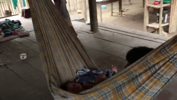 ウカイリ川からの先住民族のコミュニティのビデオ アマゾンの森 Shipibo Coniboコミュニティ 女の子で小屋休息と遊びますでハンモック — ストック動画
