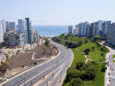 Pazar günleri Lima Peru 'nun insansız hava aracıyla yapılan hava görüntüsü. Sokağa çıkma yasağı nedeniyle özel arabalara izin verilmiyor. İnsanlar plaja doğru bisiklet sürüyorlar. Miraflores Bölgesi.