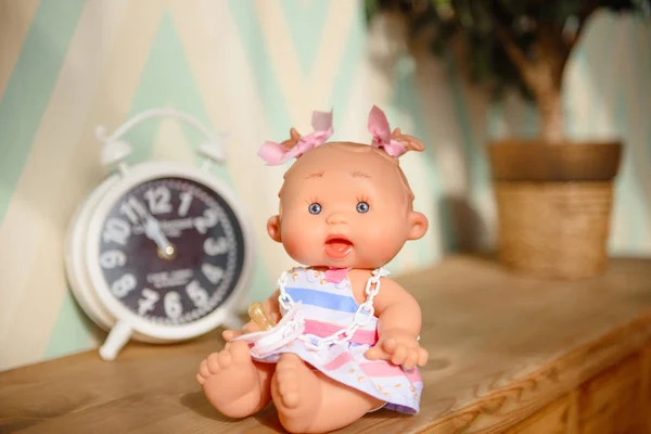 Cute doll sits on the wood background.