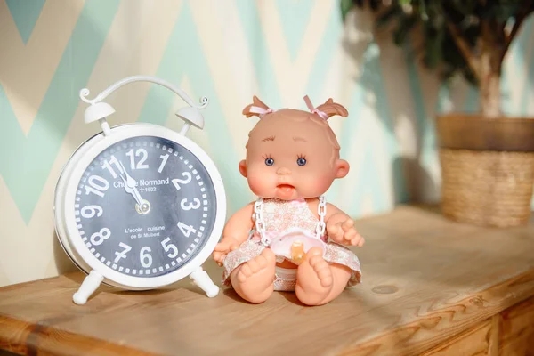 Cute doll sits on the wood background.