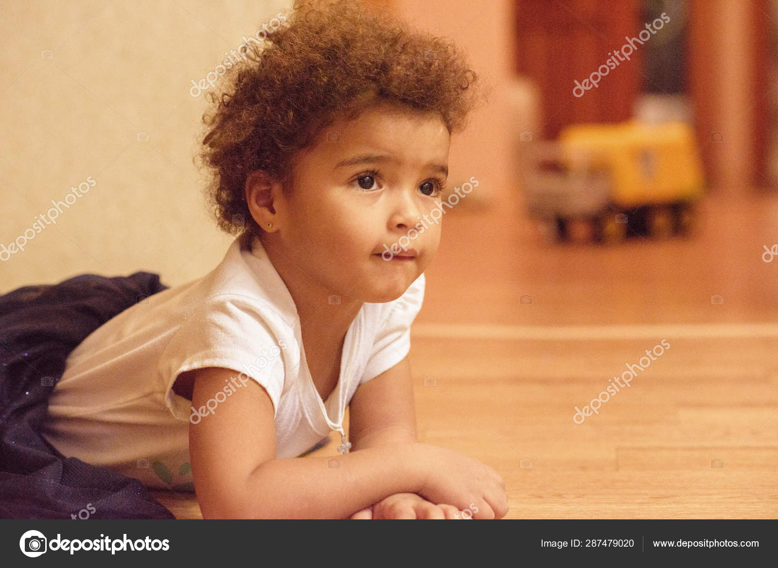 Little African American Cute Girl Laying On Floor With Smile
