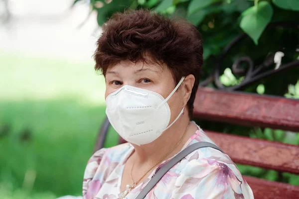 Woman wearing surgical mask epidemic prevention covering face. Senior woman in late 60s using mask looking to camera.