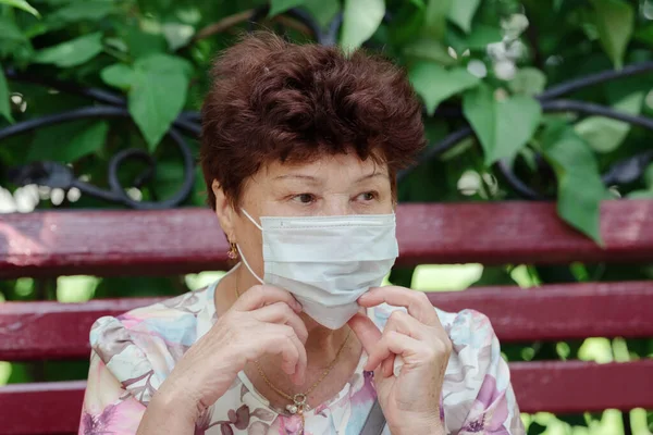 Woman wearing surgical mask epidemic prevention covering face. Senior woman in late 60s using mask looking to camera.
