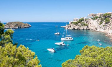 Güneşin ışıkları. Denizde yüzen tekne, kayalar ve mavi gökyüzü. Sicilya, İtalya