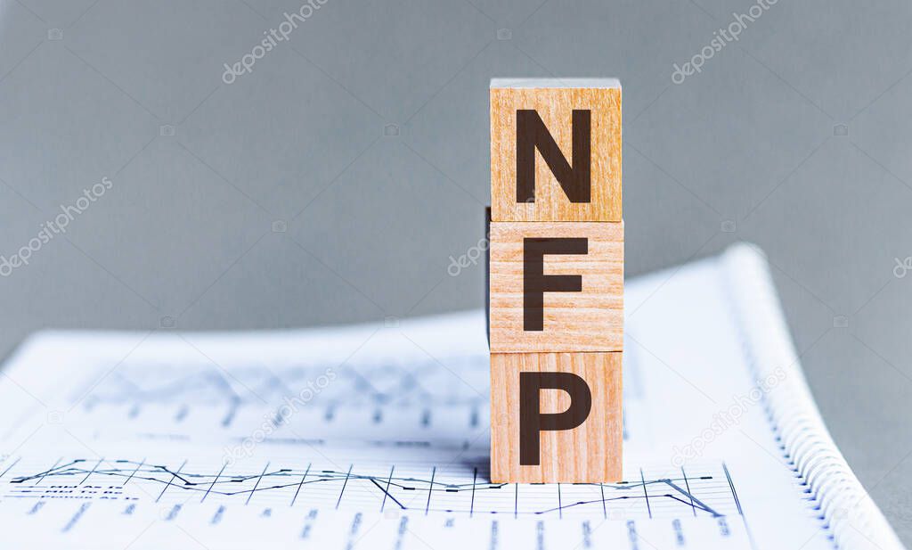 Word NFP - Non Farm Payrolls - acronym concept on cubes and diagrams on a gray background. Business as usual concept image.