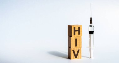 Beyaz bir masadaki tahta bloklardan oluşan HIV kısaltması. Onun yanında bir şırınga var. Hayata karşı bir tehdit. Tıbbi bir kavram..