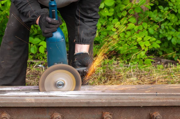 Workers cut metal products for maintenance on the railway, sparks fly.
