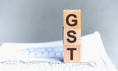 Ahşap blokta GST - kısaltma GST - Mal ve Hizmetler Vergisi. Kağıt gri arkaplanda GST tahta bloklar