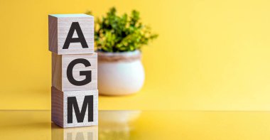 AGM - Geleneksel Genel Kurul - Sarı arka planda tahta küplerin kısaltması. İş konsepti
