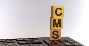 Klavyede bulunan tahta küplerdeki CMS metni, gri arkaplan