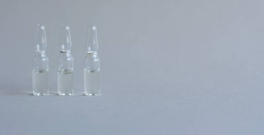 İğne için cam ampul şişesi. İlaç beyaz ilaç penisilin tozu ya da ampulla içinde sulu çözeltisi olan sıvıdır. Kapatın. Arka planda gri alüminyum kapaklı şişeler