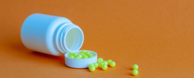 Hapları turuncu arka plandaki şişeden döktüm. Sağlık kavramı, virüslerden korunma, grip ve soğuk algınlıkları.