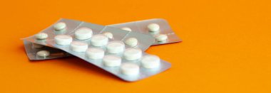 Turuncu arka planda üç adet genel tablet kabarcığı. Plastik paketlerde çeşitli haplar. Ağrı kesiciler, hormonlar, antidepresanlar, aspirinler..