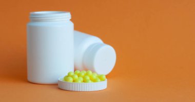 Hapları turuncu arka plandaki şişeden döktüm. Sağlık kavramı, virüslerden korunma, grip ve soğuk algınlıkları