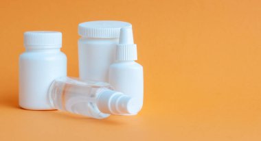 Tablet ve vitaminli üç taşınabilir plastik şişe ve masanın üzerinde dezenfektan antiseptik jel olan şeffaf bir plastik şişe. Turuncu desenli arkaplan.