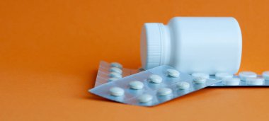 Beyaz masanın üzerinde antiseptik jel bulunan iki taşınabilir plastik şişe. Gri desenli arka plan.