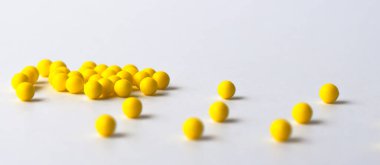 Sarı vitaminler beyaz plastik bir şişeden beyaz parlak bir masaya dökülür. Kavram. Etiket için yer. Teşhis.