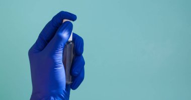 Plastik eldivendeki bir el yeşil arka plana anestezi püskürtür..