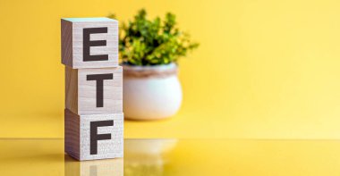 Fotokopi alanı ve iş konsepti olan sarı arkaplandaki ahşap küplerden oluşan ETF kelimesi.