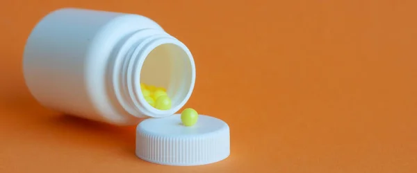 I poured the pills out of the bottle on an orange background. Concept of health, protection from viruses, flu and colds.