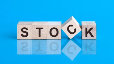 Borsa küpü üzerine metin, hisse senedi yatırım konsepti. STOCK metni küplerin üzerine siyah harflerle yazılmıştır. Küpler mavi cam bir yüzey üzerindedir..