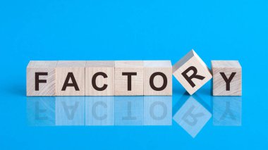 Tahta küp üzerine metin faktörü, hisse senedi yatırım konsepti. FACTORY metni küplerin üzerine siyah harflerle yazılmıştır. Küpler mavi cam bir yüzey üzerindedir..
