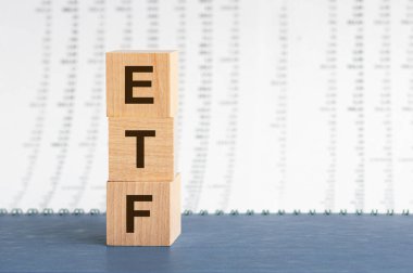 ETF 'nin tahta metin blokları. İş ve finansal konsept. konsept resim bir ahşap blok ve kelime ETF - takas fonu - gölge seçici odaklı bir sıra bloklar gri bir defter üzerinde yer almaktadır. Sayılar sütunlarının arkaplanı, ön görünüm.