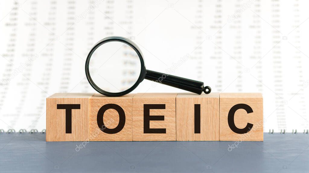Toeic word on wooden cubes. Wooden Blocks with the text: TOEIC and with magnifying glass. Educational concept