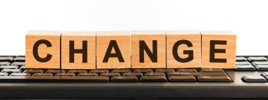 Yapı taşlarından yapılmış kelimeyi değiştir. Siyah yazı tipiyle yazılmış bir sıra tahta küp siyah bir klavyede yer almaktadır..