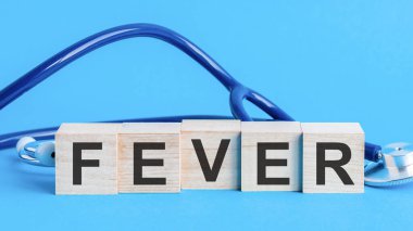 İnşaat taşlarından yapılmış ateşli bir kelime. Sözcüklerle ahşap blok Masada steteskop ile ateş, sigorta ve tıbbi konsept, mavi arka plan