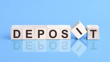 Tahta küp bloğu, hisse senedi yatırım konsepti hakkında metin yaz. DEPOSIT metni küplerin üzerine siyah harflerle yazılmıştır, küpler mavi cam bir yüzey üzerindedir..