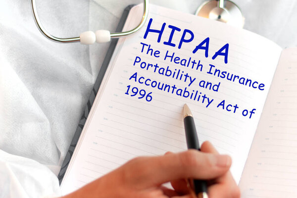 Doctor holding a card with text HIPAA - Health Insurance Portability and Accountability Act, medical concept. The text is written in blue letters in a medical journal.