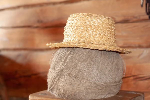 An old straw hat hangs on a ball of gray linen thread. Electoral focus Straw Hat hanging in the green garden. Selective focus