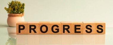 Progres 'in küplerle ilgili metni. ProGRESS mesaj sözcüğü arkaplanda bir çiçekle küp bloklardaki ahşap bir masa üzerinde