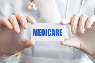 Sağlık Sigortası - Tıp Doktoru bilgi gösteriyor. Doktor elinde sağlık sigortası mesajı olan bir kart tutuyor. Tıbbi konsept,