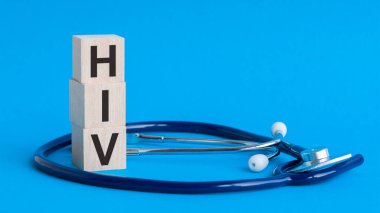 Tahta bloklara yazılmış HIV kelimesi ve açık mavi arka planda steteskop. sigorta ve tıbbi konsept