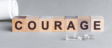 Tahta bloklardaki yazılar. Bir sıra küpün önünde ampuller, arka planda - tabletlerden alınan beyaz plastik ambalajlar, gri bir yüzey üzerinde yer almaktadır. Resmi Kabul Et.